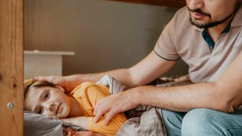 Boy lying on bed with father caressing him at home model released, Symbolfoto property released, ANAF02226