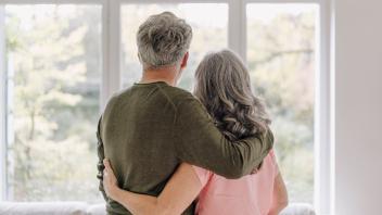 Rear view of senior couple looking out of window at home model released Symbolfoto property released PUBLICATIONxINxGERx