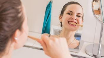 Frau putzt sich mit einer Bambus-Zahnbürste die Zähne