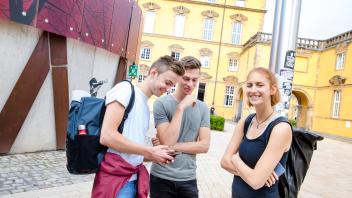 Drei Studierende stehen vor dem Universitätsgebäude der Universität Osnabrück
