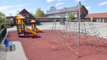 Auf dem Schulhof der David-Fabricius-Grundschule Osteel ist ein großer Spielplatz mit Rutsche, Schaukeln und Klettergerüst. 