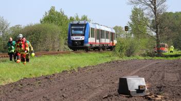 Das Foto zeigt das Front-Gewicht des Treckers, der am Bahnübergang mit dem Zug kollidierte. In Hintergrund sind Helfer und der Zug zu sehen.