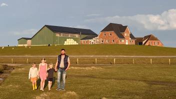 Nommen Kruse mit seinen Kindern vor der neuen Klimawarft, die deutlich höher liegt als der Altbau.