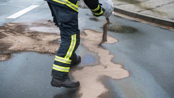 Ölspur Aufbringen von Ölbindemittel auf eine mit Öl verschmutzte Straße. Deutschland *** Oil trace Application of oil bi