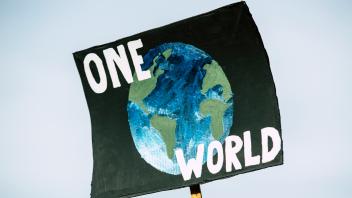Ein Plakat zeigt den Planeten Erde mit der Aufschrift „One World“ (Eine Welt)