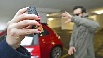 Symbolfoto Frau wehrt einen Angreifer mithilfe von Pfefferspray in einem Parkhaus vor ihrem Auto ab