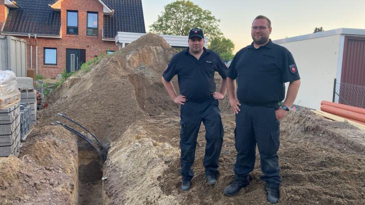 Jann Kirchner (links) und Lukas Ahrens vom Kampfmittelräumdienst zeigen den Fundort der Granate nach der Sprengung.