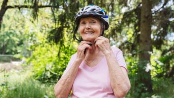 Smiling senior woman wearing cycling helmet in park model released, Symbolfoto, OSF00940