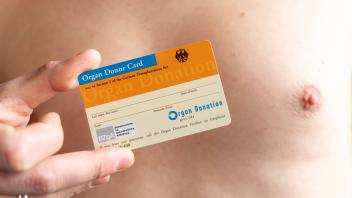 Augsburg, Bavaria, Germany - January 14, 2024: Man with bare upper body holding an organ donor card *** Mann mit freiem 