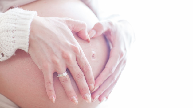 The lady puts her hand on her baby bauch