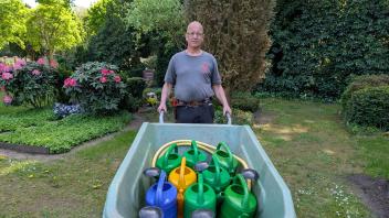 Arbeit im Akkord: Gärtner Michael Asmussen ist auf dem Friedhof in Neumünster gleich mit mehreren Gießkannen gegen die Trockenheit im Einsatz.