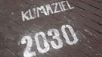 Aufmerksamkeit zu dem Klimaschutzprogramm Auf den Pflastersteinen von einem Gehweg wurde mit Hilfe einer Schablone der T
