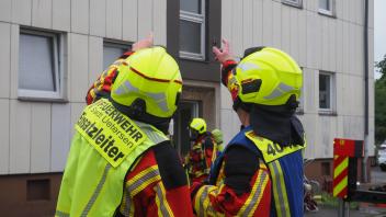 Die Einsatzleitung bespricht das weitere Vorgehen. Ein weiterer Feuerwehrmann ist auf dem Weg ins Mehrfamilienhaus.