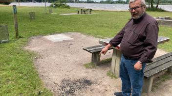 Einfelds Stadtteilvorsteher Manfred Zielke zeigt auf Holzkohlereste, die nach dem Grillen einfach auf dem Boden landeten. Auf den Gewegplatten im Hintergrund standen bis vorige Woche noch zwei der vier Grillstationen an der Einfelder Schanze. 