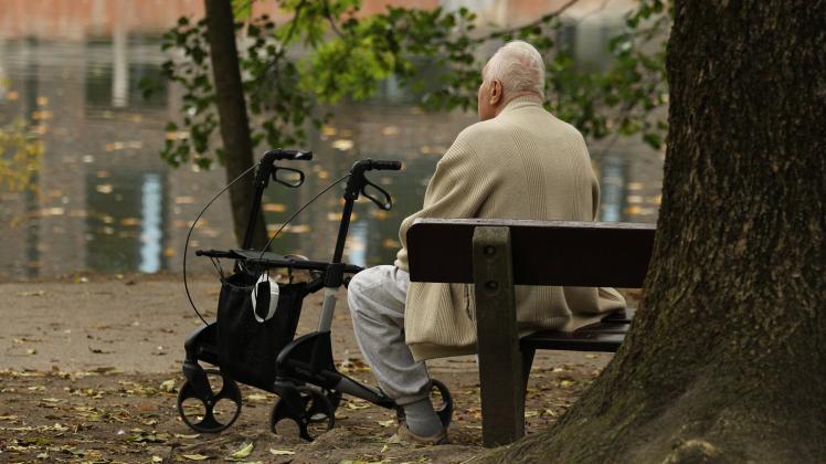 Ein alter Mann sitzt alleine auf einer Parkbank. Neben ihm steht sein Rollator. Symbolbild/Symbolfoto Einsamkeit im Alter